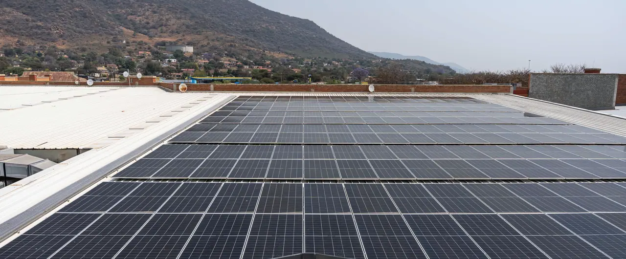 Rows of solar modules on the Moruleng Mall roof, with a long mountain ridge beyond
