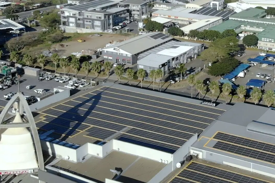 Rows of solar modules across the Ballito Lifestyle Centre roof, with office buildings and palms beyond