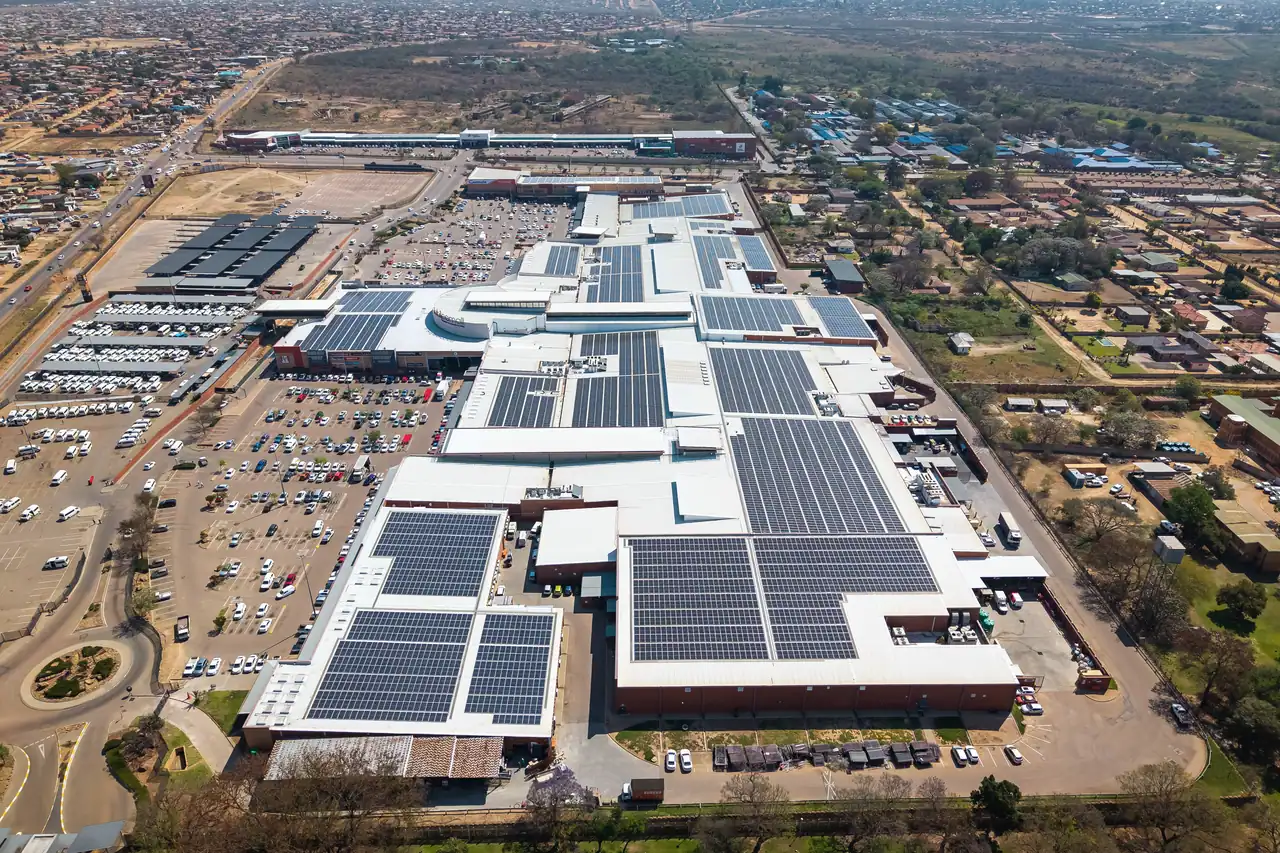 Aerial view of Jubilee Mall, its roofs covered in blocks of solar modules, with the car parks and the town around it