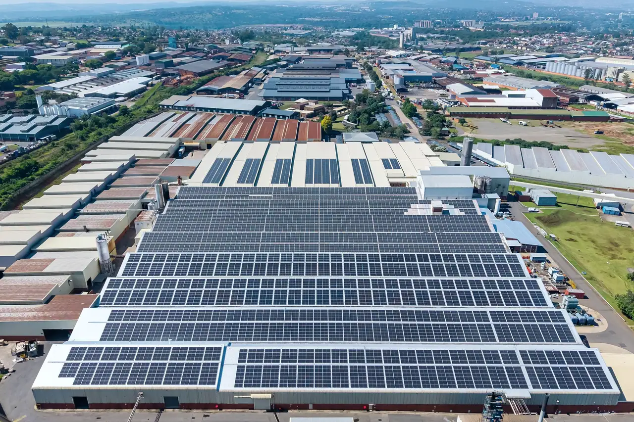 Belgotex, rooftop solar plant: rows of solar modules along the factory roof, with Pietermaritzburg beyond