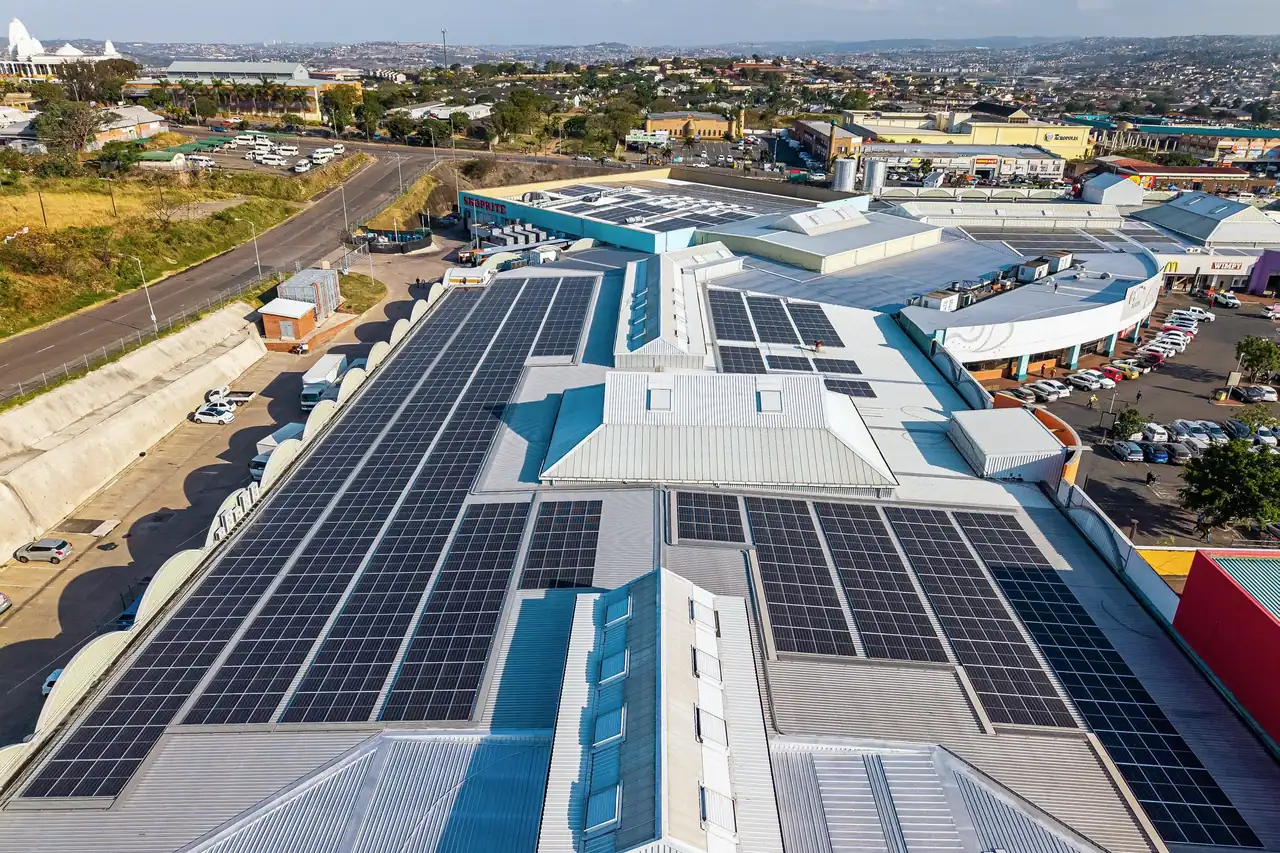 Aerial view of Phoenix Plaza, its roofs covered in solar modules, with the car park and the town beyond